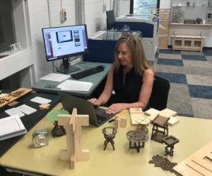 image of Marlo Ransdell working in the shop on several small scale models of various objects of an interior design